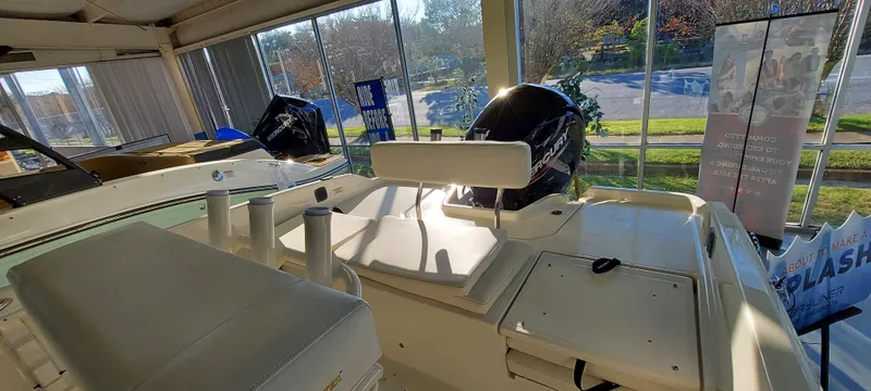 Slide: The Image of 2023 Bayliner Trophy T21Bay boat interior in showroom, featuring seating and engine. - 5