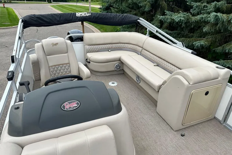 Slide: The Image of 2023 Ranger Reata 223C pontoon boat interior with beige seating and steering console. - 16