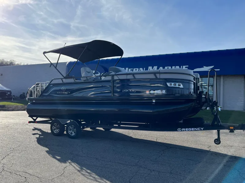 Slide: The Image of 2023 Regency 230 LE3 Sport pontoon boat on trailer outside dealership. - 0