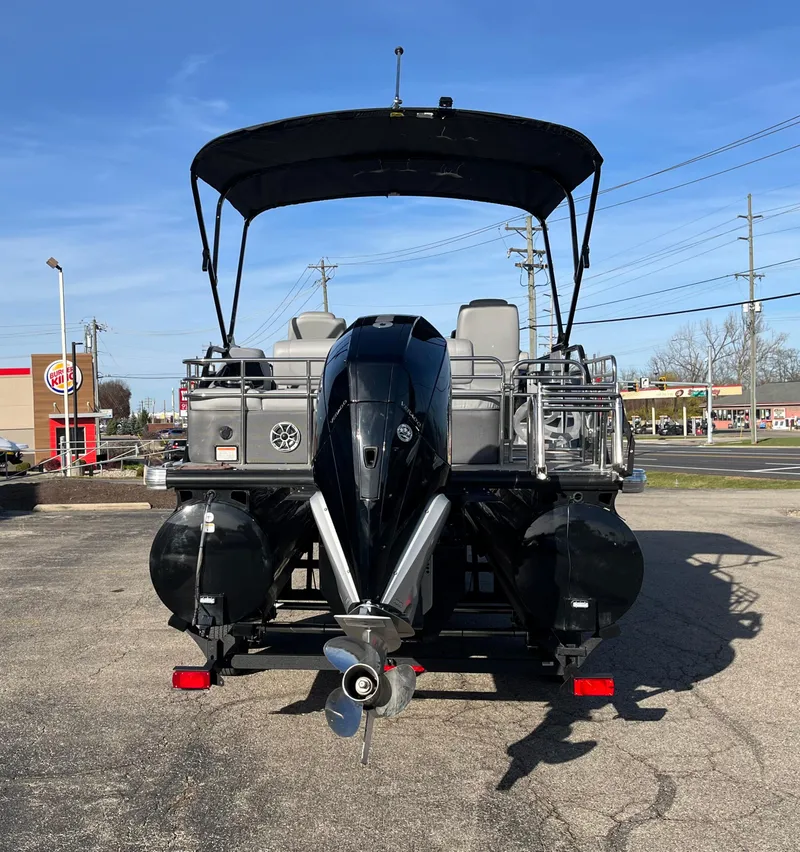 Slide: The Image of 2023 Regency 230 LE3 Sport pontoon boat with outboard motor, parked on pavement. - 10