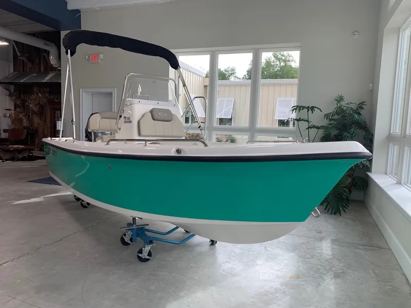 Slide: The Image of 2024 Key West 1720 Sportsman boat in showroom, teal hull, white interior, black bimini top. - 1