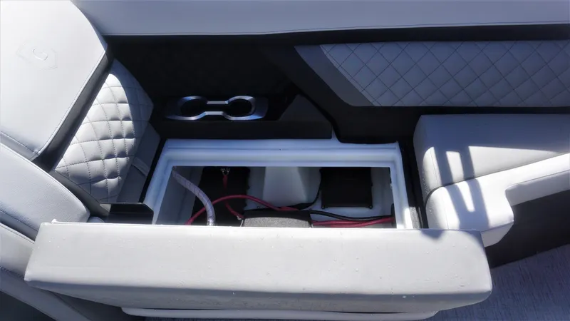 Slide: The Image of 2023 AquaPatio 235 ULC boat interior with open storage compartment and cup holders. - 20