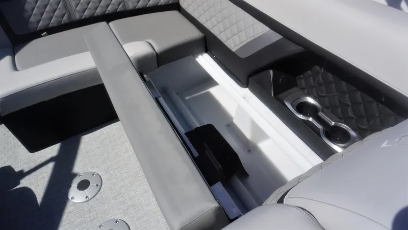 Slide: The Image of 2023 AquaPatio 235 ULC boat interior with storage compartment and cup holders. - 21