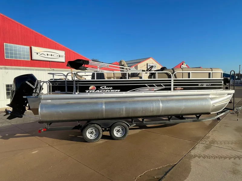 The Image of 2023 Sun Tracker SportFish 22 XP3 pontoon boat on trailer, parked outside dealership. - 0