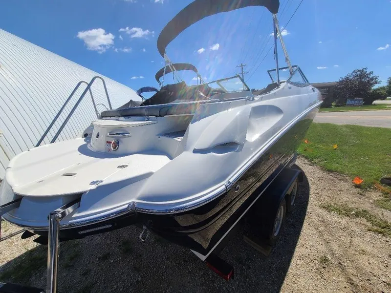 Slide: The Image of 2022 Stingray 215LR boat with sleek design and black hull, parked outdoors. - 5