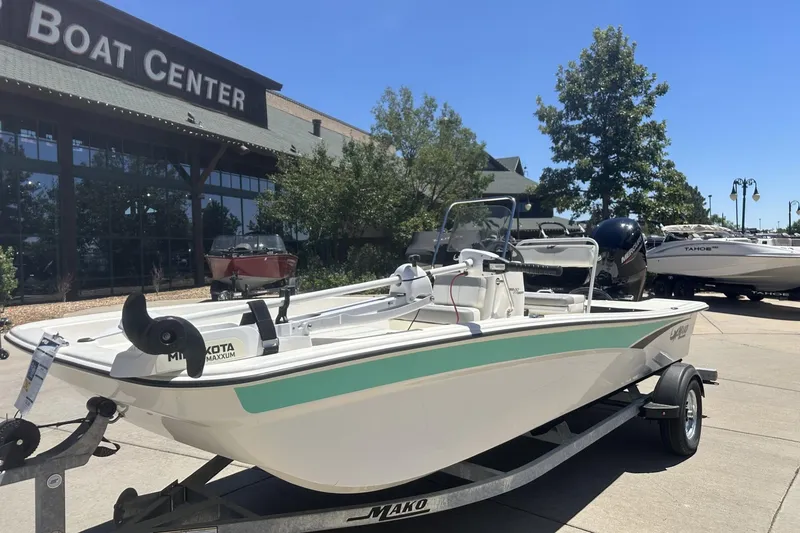 Slide: The Image of 2023 Mako Pro Skiff 17 CC boat on trailer outside a boat center. - 2