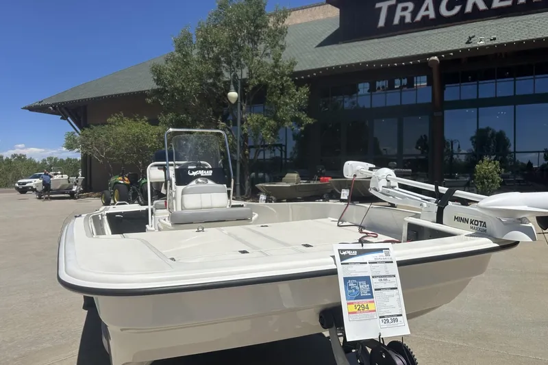 Slide: The Image of 2023 Mako Pro Skiff 17 CC boat displayed outside a Tracker store. - 3