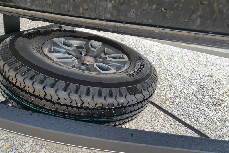 Slide: The Image of Spare tire mounted under a 2023 Tracker Pro Team 190 TX boat trailer. - 19