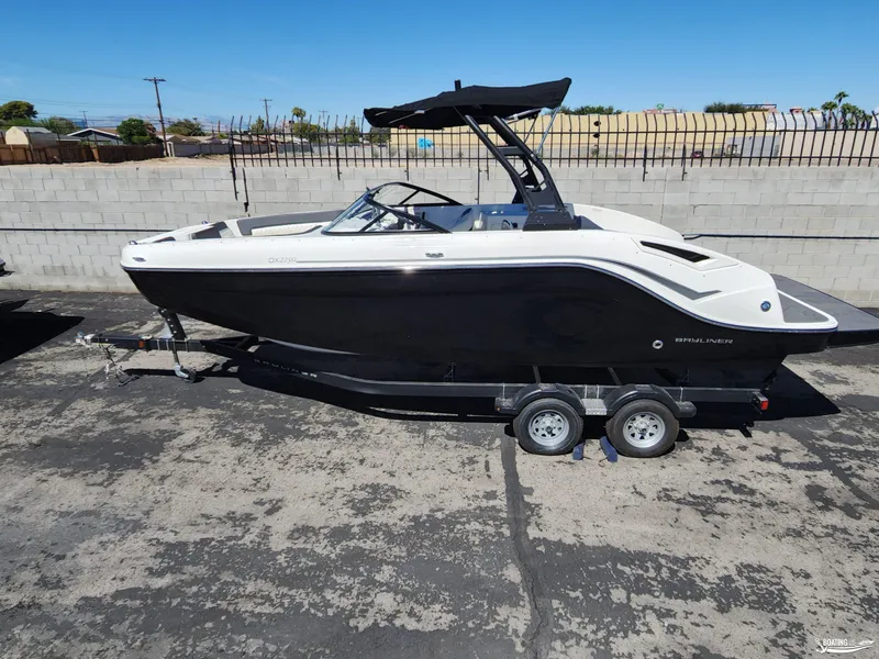 Slide: The Image of 2023 Bayliner DX2250 boat on trailer, black and white design, parked outdoors. - 0