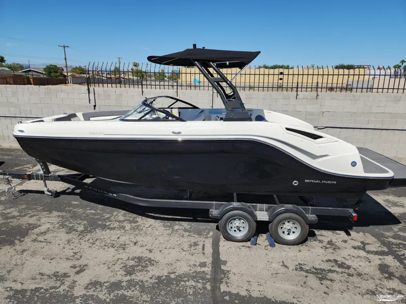 Slide: The Image of 2023 Bayliner DX2250 boat on trailer, black and white design, parked outdoors. - 1