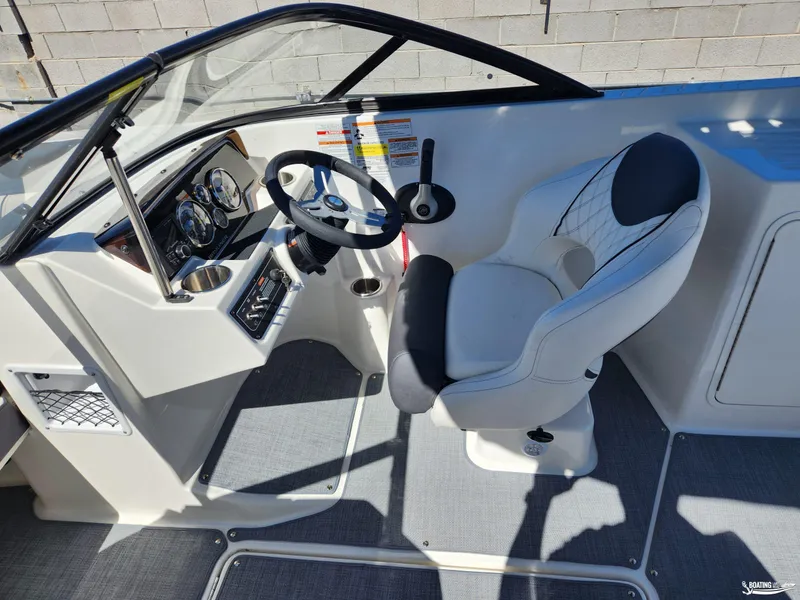 Slide: The Image of 2023 Bayliner DX2250 boat cockpit with steering wheel and captain's chair. - 12