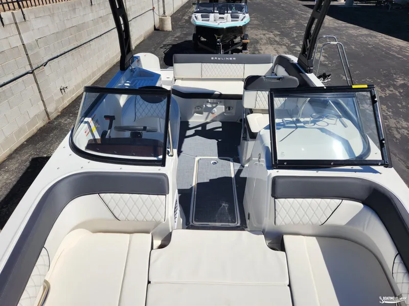 Slide: The Image of 2023 Bayliner DX2250 boat interior with seating and windshield, docked outdoors. - 23