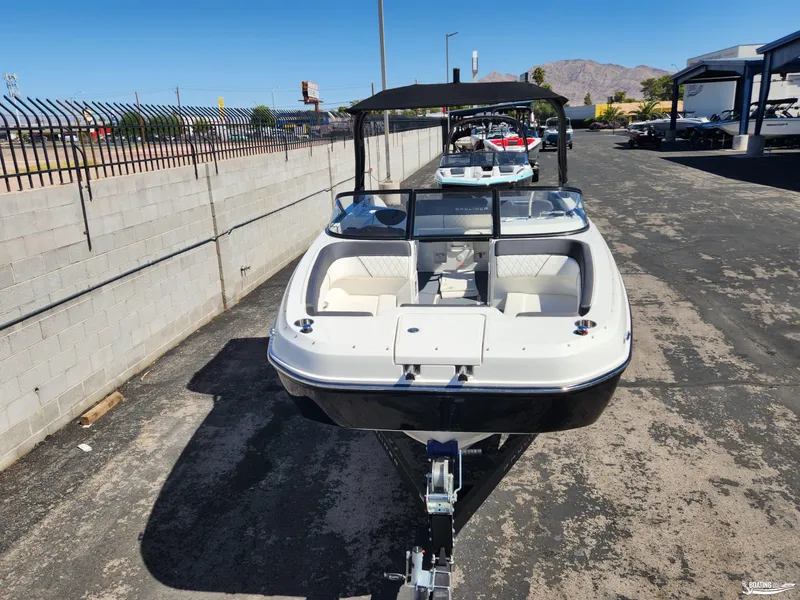 Slide: The Image of 2023 Bayliner DX2250 boat on trailer, parked outdoors, with mountains in background. - 4