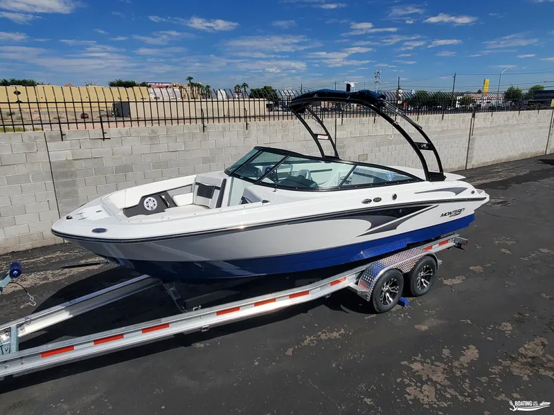Slide: The Image of 2023 Monterey M22 boat on trailer, parked outdoors under blue sky. - 2
