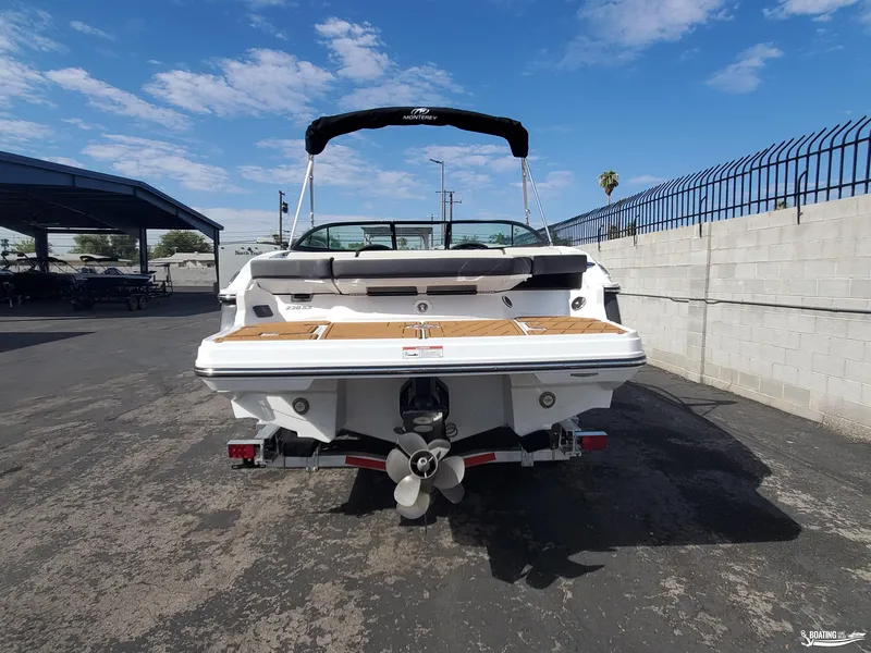 Slide: The Image of 2023 Monterey 238SS boat rear view, parked outdoors under a clear sky. - 6