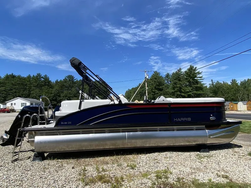 Slide: The Image of 2023 Harris Cruiser 230 CWDH pontoon boat on gravel lot with trees in background. - 0