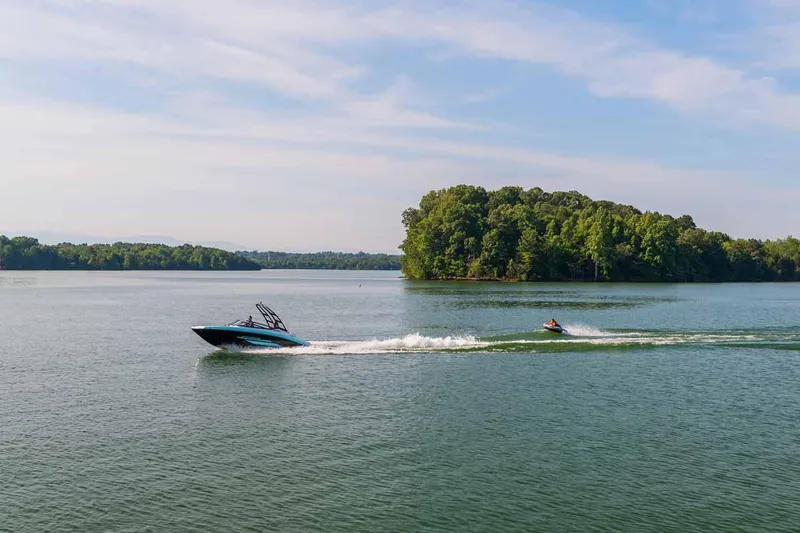 Slide: The Image of 2023 Yamaha Boats AR195 cruising on a serene lake near a lush island. - 13