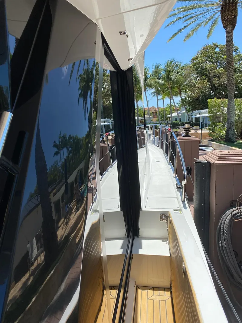 Slide: The Image of 2022 Galeon 470 Skydeck yacht docked, featuring sleek design and tropical surroundings. - 6