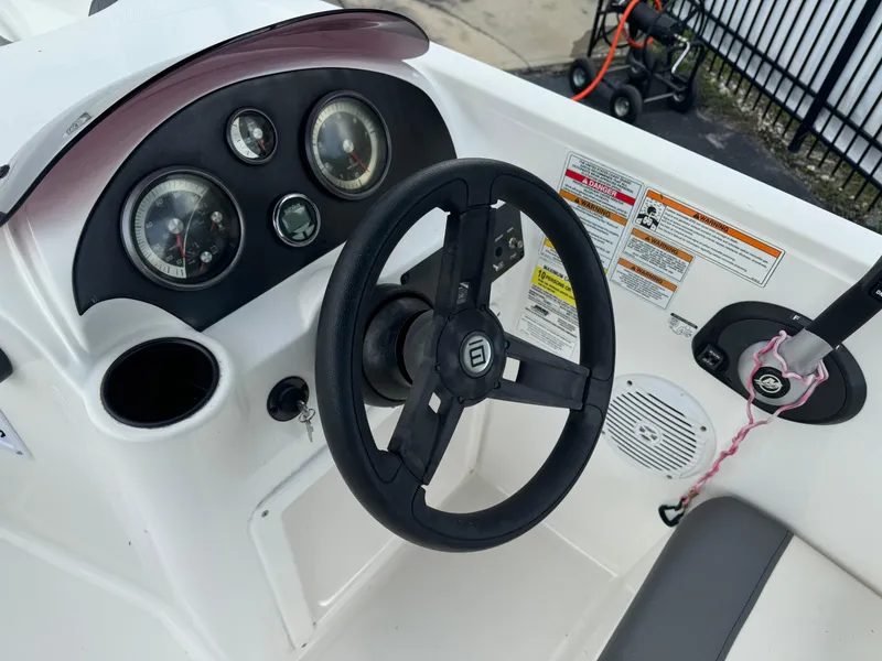 Slide: The Image of 2023 Bayliner E21 boat dashboard with steering wheel and gauges. - 2