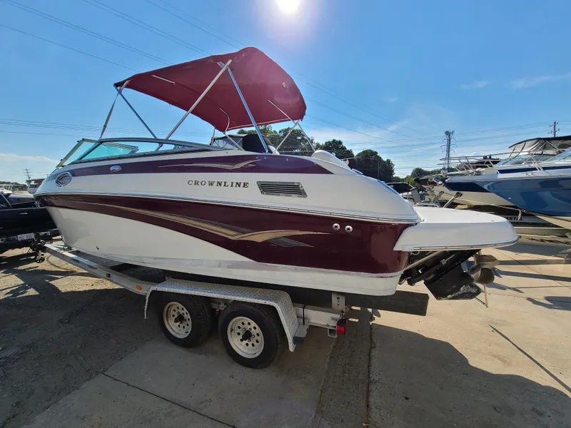 Slide: The Image of 2003 Crownline 230BR boat with red canopy on trailer in marina. - 2