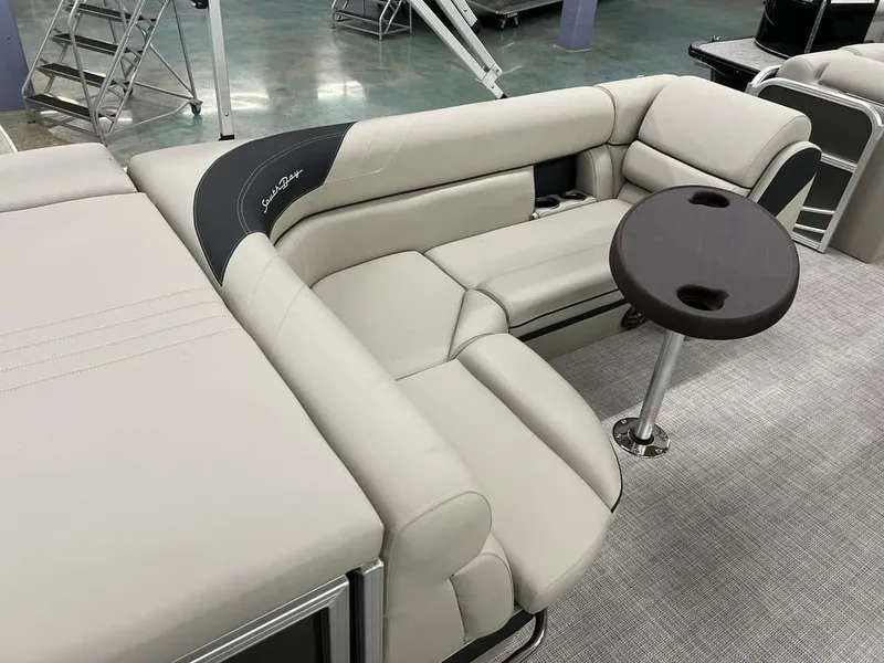 Slide: The Image of 2023 South Bay 222 CR LE 2.75 pontoon boat interior with beige seating and small table. - 10