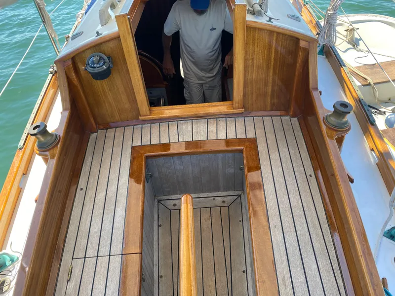 Slide: The Image of Laurent Giles Vertue Class Sloop 2010, wooden deck, open hatch, person entering cabin. - 20