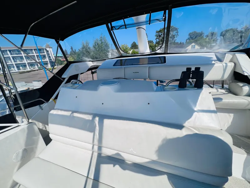 Slide: The Image of 1999 Silverton 392 Motor Yacht interior with seating and helm, featuring binoculars and cup holders. - 11