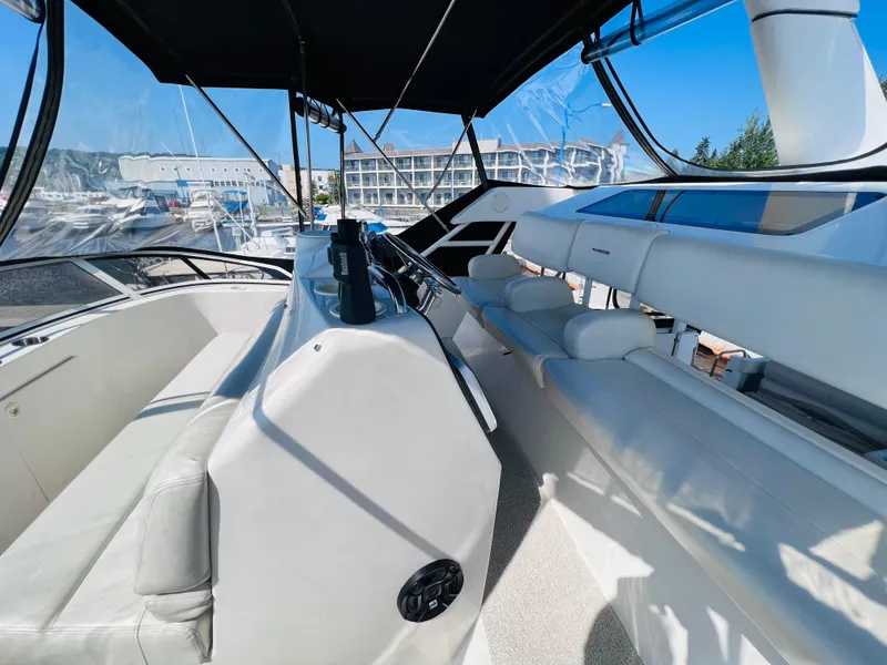 Slide: The Image of 1999 Silverton 392 Motor Yacht interior with white seating and helm, docked at marina. - 14