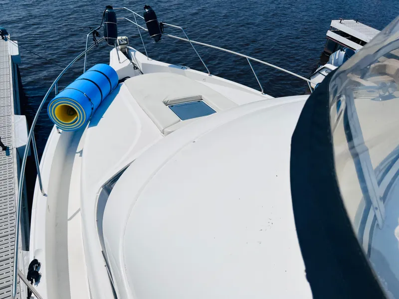 Slide: The Image of 1999 Silverton 392 Motor Yacht docked, featuring a blue rolled mat on deck. - 15