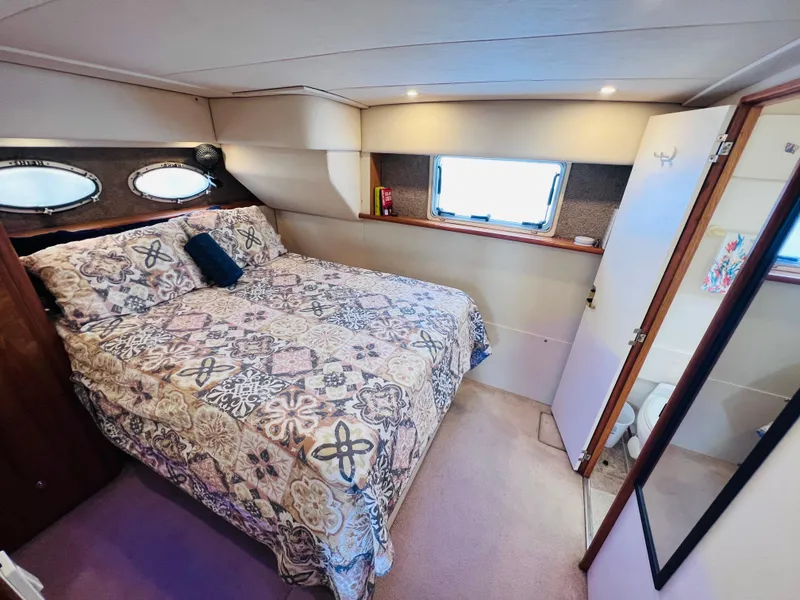 Slide: The Image of 1999 Silverton 392 Motor Yacht bedroom with patterned bedding and porthole windows. - 21