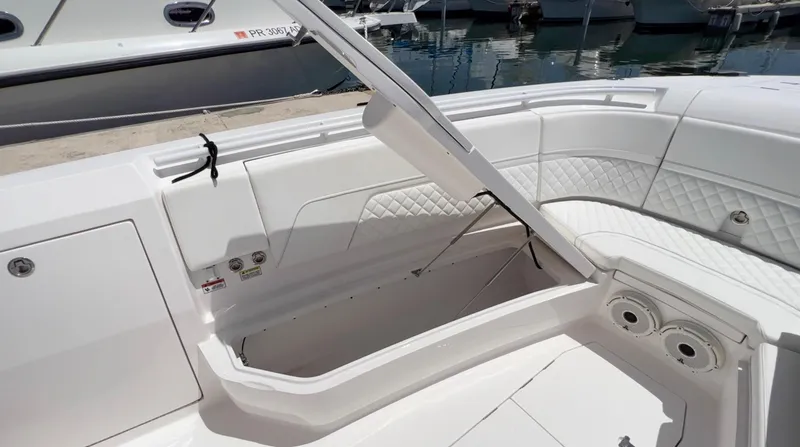 Slide: The Image of 2020 Intrepid 345 Nomad boat with open storage compartment, white interior, and quilted seating. - 12