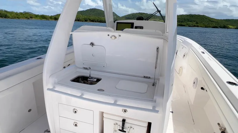 Slide: The Image of 2020 Intrepid 345 Nomad boat interior with sink and storage, set against a scenic water backdrop. - 5