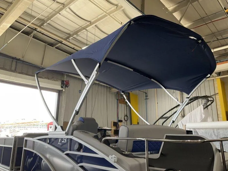 Slide: The Image of 2023 Bennington 25 LTSB pontoon boat with blue canopy in a warehouse. - 13