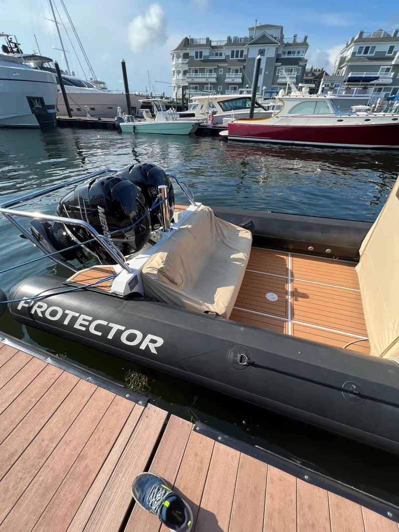 Slide: The Image of 2020 Protector 330 Targa boat docked at marina with luxury yachts in background. - 12