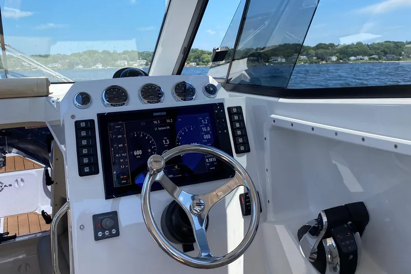 Slide: The Image of 2020 Protector 330 Targa boat cockpit with modern navigation controls and scenic water view. - 26