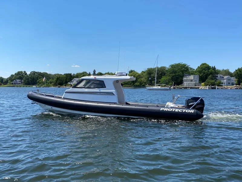 Slide: The Image of 2020 Protector 330 Targa boat cruising on a sunny day in a scenic waterway. - 27