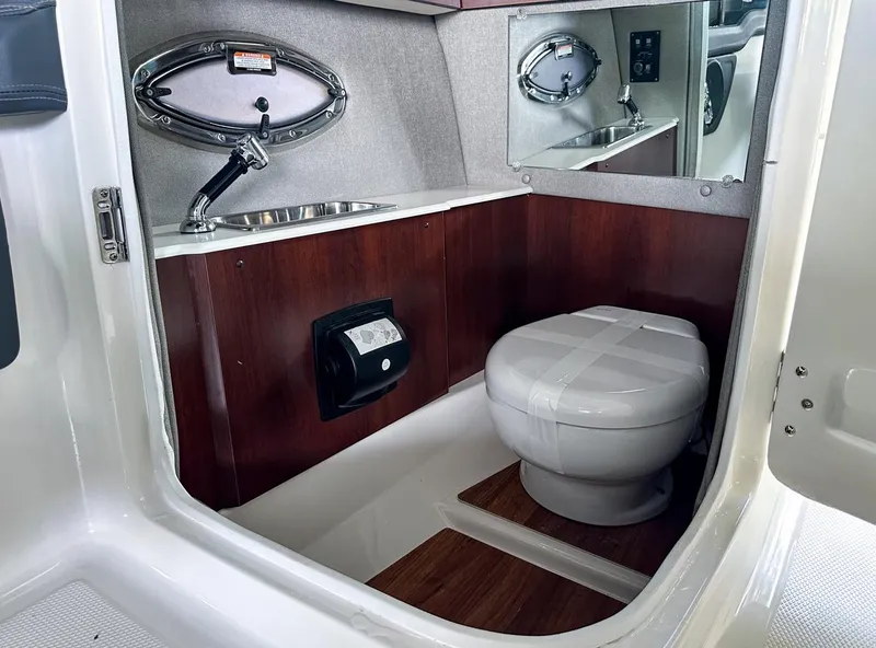 Slide: The Image of 2025 Chaparral 270 OSX OB boat bathroom with sink, mirror, and toilet. - 21