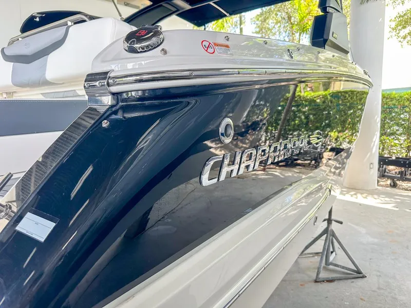 Slide: The Image of 2025 Chaparral 270 OSX OB boat, sleek design, docked in a shaded area. - 5