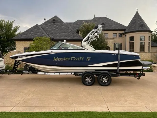 Slide: The Image of 2015 MasterCraft X-55 boat on trailer in front of luxury home. - 0