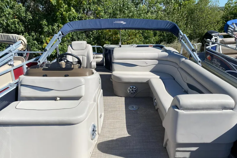 Slide: The Image of 2018 Bennington 22 SFX pontoon boat with spacious seating and canopy, surrounded by greenery. - 7