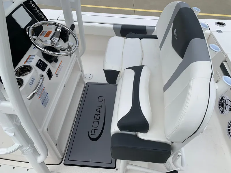 Slide: The Image of 2026 Robalo 246 Cayman Sky Deck boat interior with steering console and cushioned seating. - 9
