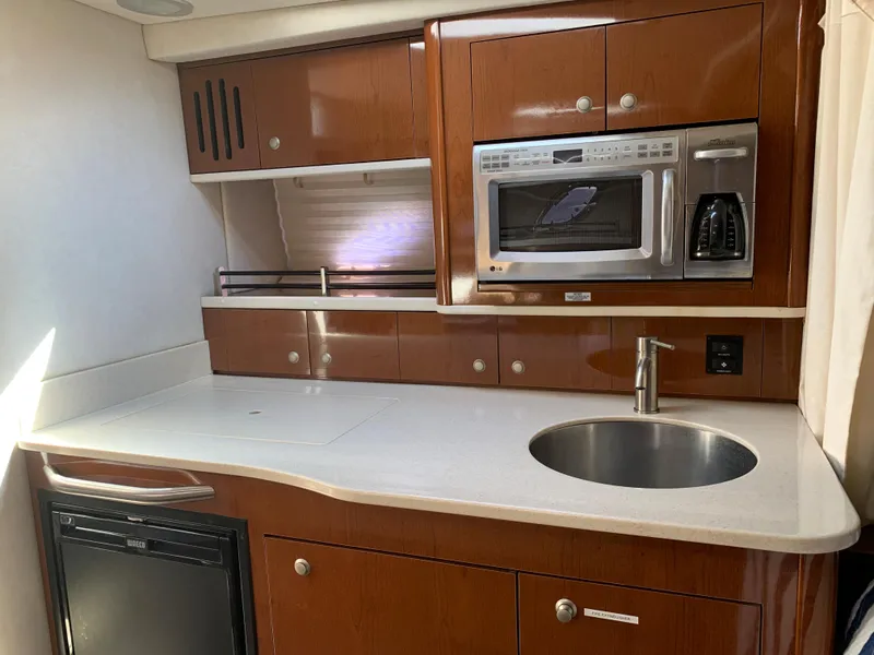Slide: The Image of 2008 Sea Ray 330 Sundancer yacht kitchen with microwave, sink, and wooden cabinetry. - 19