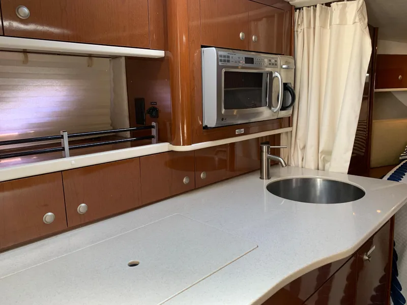 Slide: The Image of 2008 Sea Ray 330 Sundancer kitchen with microwave, sink, and wooden cabinetry. - 21