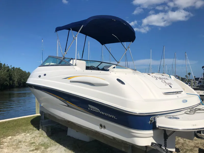 Slide: The Image of 2003 Chaparral 215 SS Cuddy boat with blue canopy docked by the water. - 5