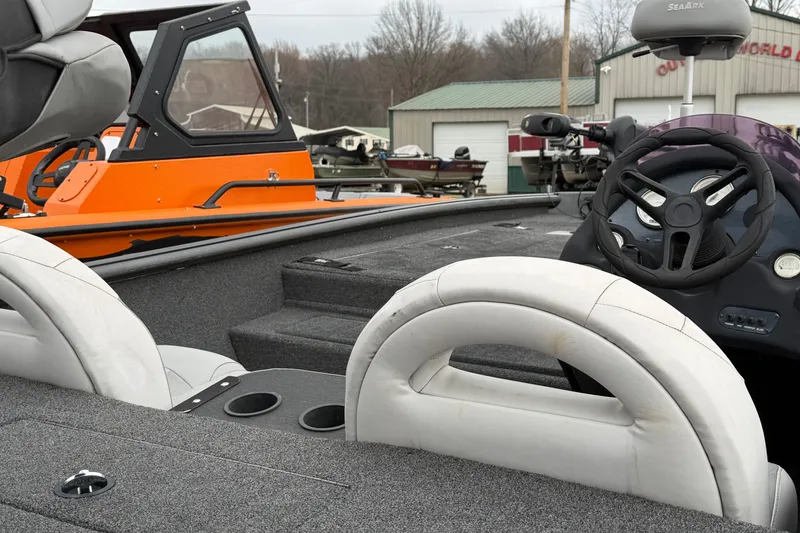 Slide: The Image of 2022 SeaArk Stealth 210 boat interior with steering wheel and seating, outdoor setting. - 12