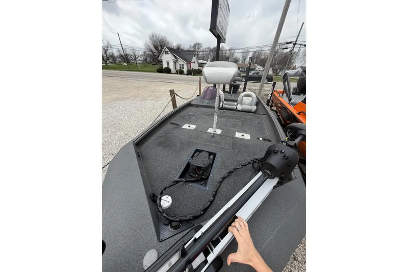 Slide: The Image of 2022 SeaArk Stealth 210 boat deck with seating and equipment, parked outdoors. - 3