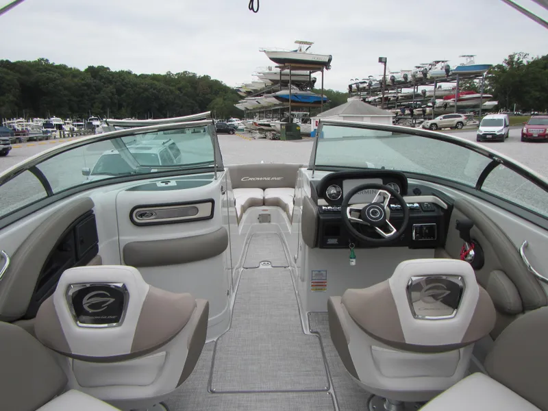 Slide: The Image of 2023 Crownline 270 SS boat interior with modern dashboard and seating at marina. - 18