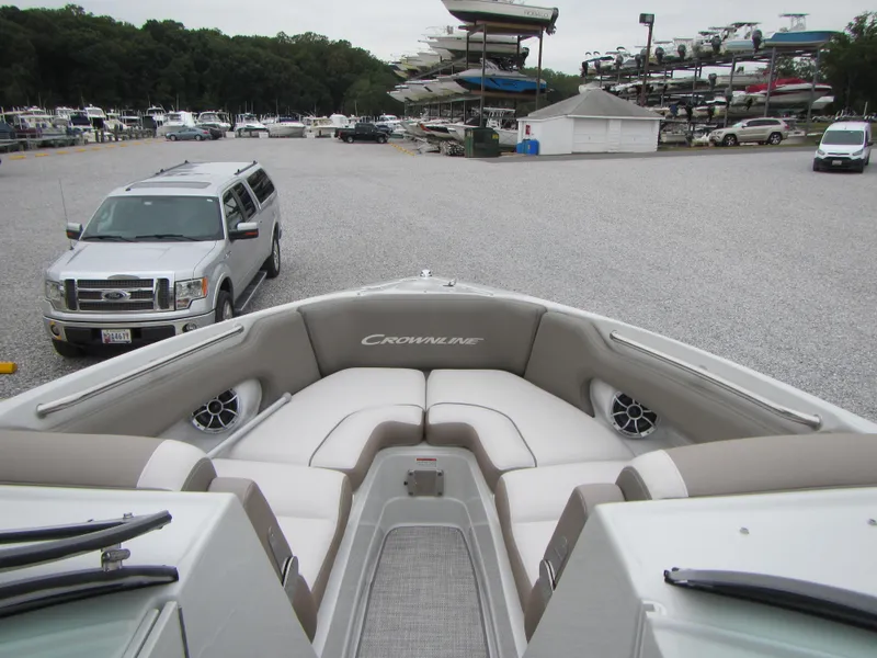 Slide: The Image of 2023 Crownline 270 SS boat with spacious seating, parked near vehicles and other boats. - 19