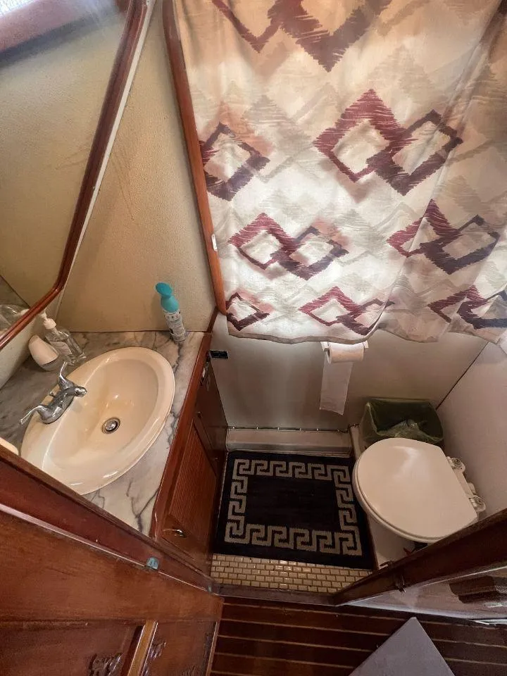 Slide: The Image of Bathroom in a 1987 Marine Trader 62 Med Yacht with sink, toilet, and patterned shower curtain. - 37