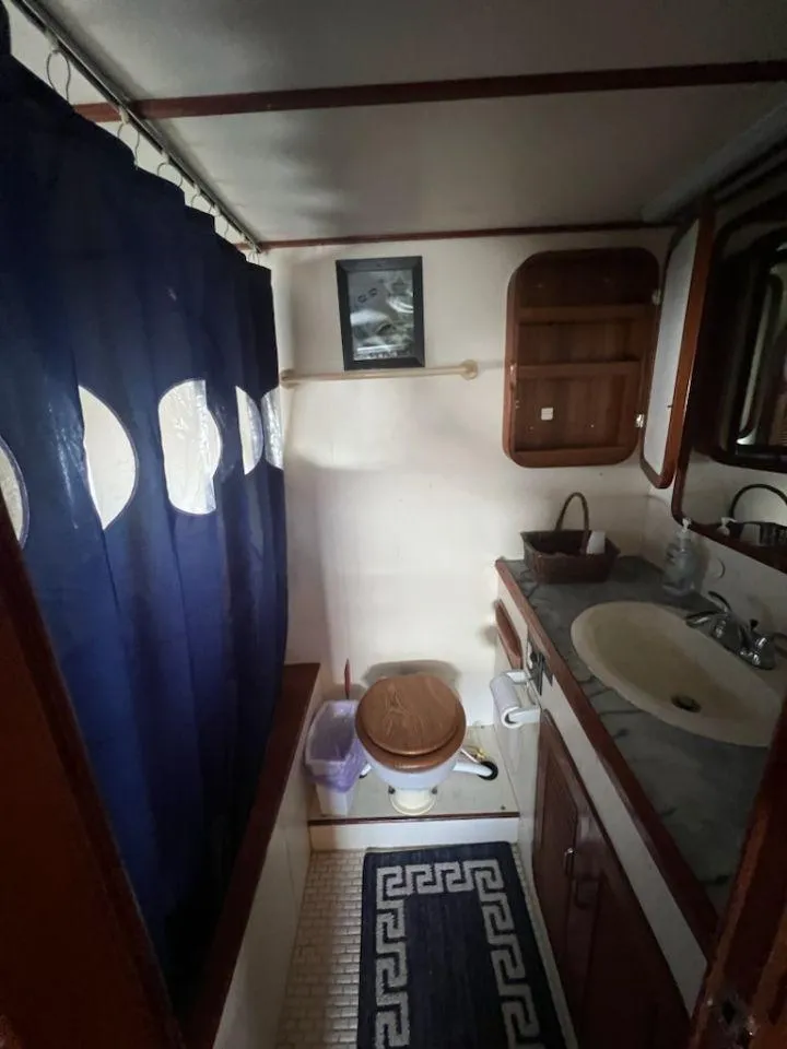Slide: The Image of 1987 Marine Trader 62 Med Yacht bathroom with sink, toilet, and shower curtain. - 39